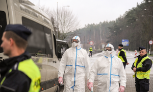 Policjanci a na pierwszym planie osoby ubrane w specjalne kombinezony