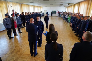 Komendant podaję rękę policjatowi i przekazuje mu teczkę z dokumentami