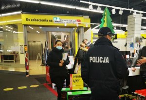 Policjant wraz z pracownikiem sanepidu w galerii handlowej kontroluje działalność sklepów