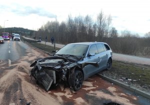 Pojazdy uszkodzone w wyniku wypadku drogowego, w tle pracują policjanci i strażacy