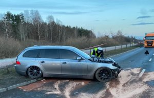 Pojazdy uszkodzone w wyniku wypadku drogowego, w tle pracują policjanci i strażacy