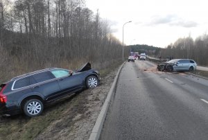 Pojazdy uszkodzone w wyniku wypadku drogowego, w tle pracują policjanci i strażacy