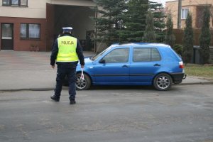 Policjant zatrzymujący samochód osobowy do kontroli drogowej