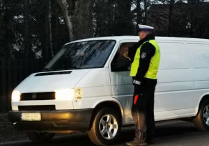 Policjanci ruchu drogowego kontrolujący pojazdy i rozdający gadżety kierowcom
