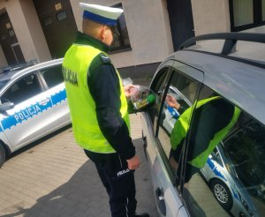 Policjanci ruchu drogowego kontrolujący pojazdy i rozdający gadżety kierowcom