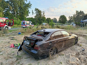 Pojazd bmw z uszkodzeniami na tle domu i uszkodzonego ogrodzenia posesji