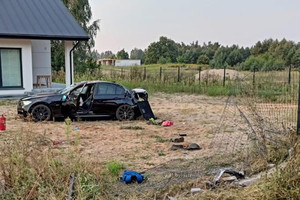 Pojazd bmw z uszkodzeniami na tle domu i uszkodzonego ogrodzenia posesji