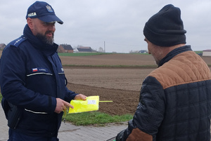 policjant wręcza rowerzyście elementy odblaksowe