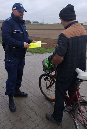 policjant wręcza rowerzyście elementy odblaskowe