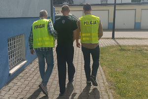 policjanci z wydziału kryminalnego prowadzą oprawcę psa